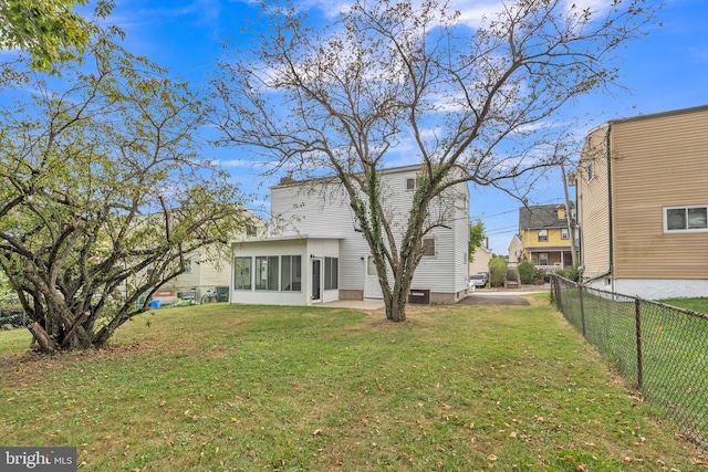 back of property featuring a lawn, a patio area, and a sunroom