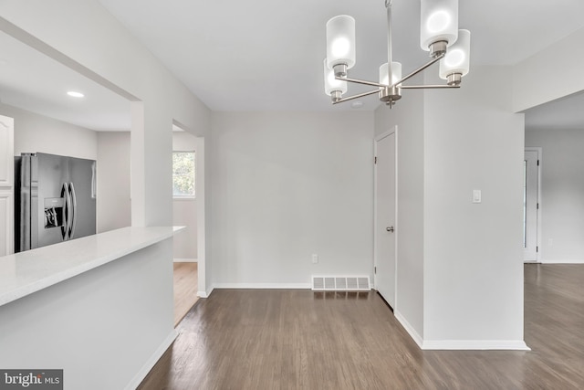 unfurnished dining area featuring dark hardwood / wood-style floors and a notable chandelier