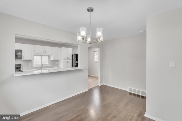 kitchen featuring stainless steel fridge, pendant lighting, white cabinetry, and a healthy amount of sunlight