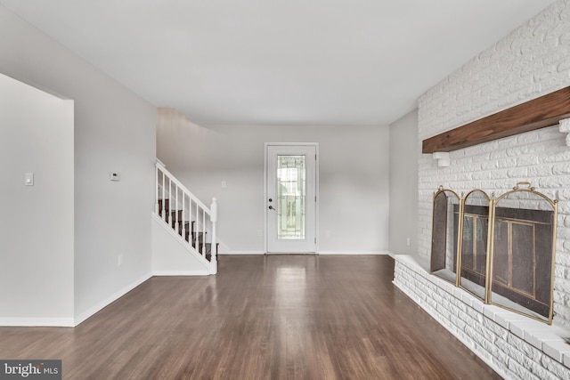 unfurnished living room with dark hardwood / wood-style floors and a brick fireplace