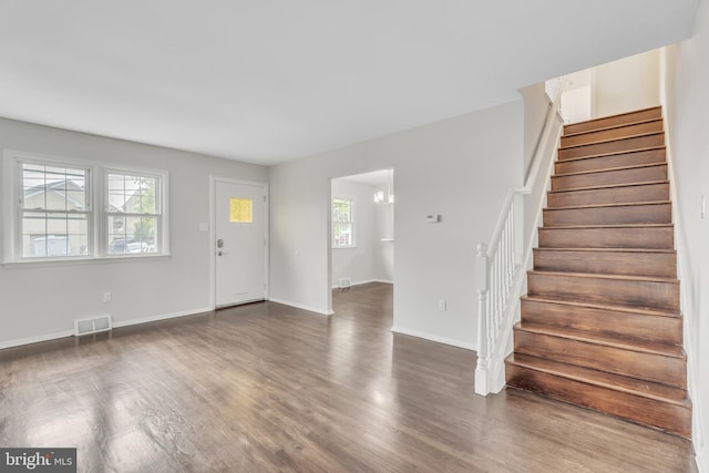 entryway with a healthy amount of sunlight, dark hardwood / wood-style floors, and an inviting chandelier