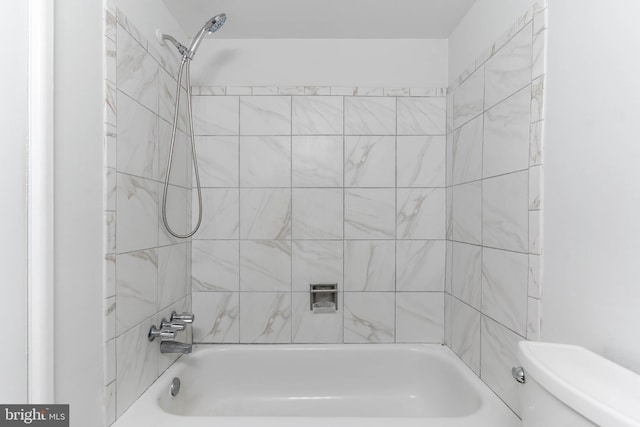 bathroom with tiled shower / bath combo and toilet