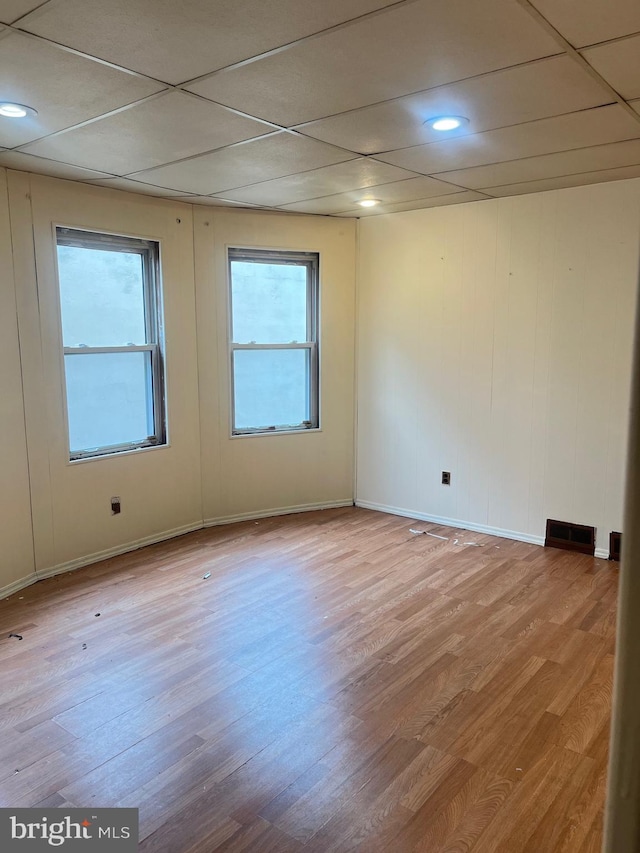 spare room featuring light wood-type flooring and a paneled ceiling