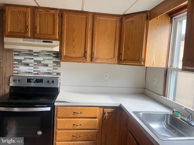 kitchen featuring electric stove, tasteful backsplash, and sink