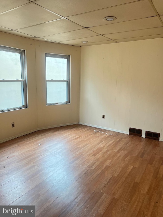 spare room with a paneled ceiling, light hardwood / wood-style floors, and a wealth of natural light