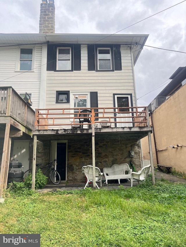 back of house featuring a lawn and a wooden deck