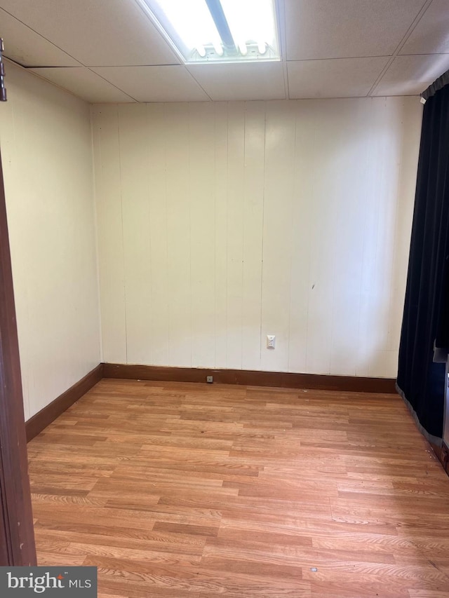 empty room with light hardwood / wood-style flooring and a drop ceiling