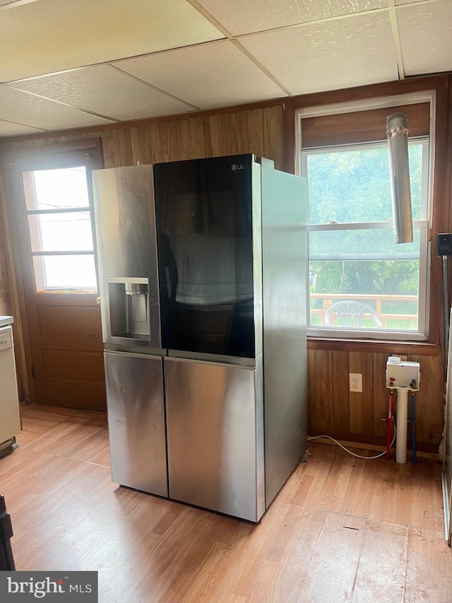 kitchen featuring white dishwasher, wood walls, a paneled ceiling, stainless steel fridge with ice dispenser, and light wood-type flooring