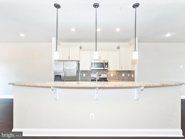 kitchen with light stone countertops, hanging light fixtures, white cabinetry, and stainless steel appliances