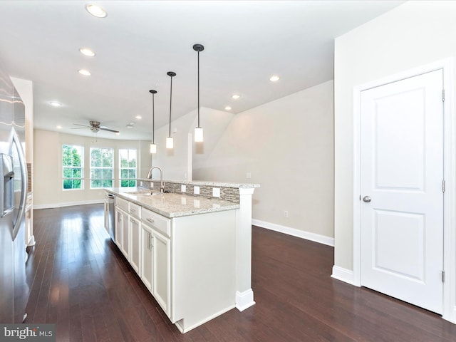 kitchen featuring a kitchen island with sink, white cabinets, dark wood-type flooring, sink, and pendant lighting