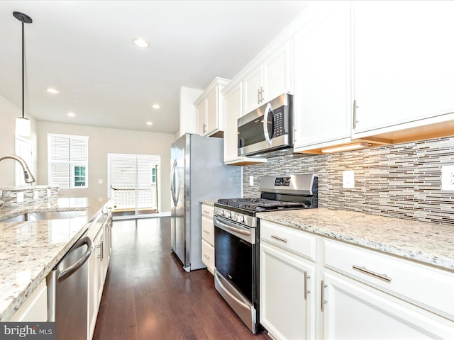 kitchen featuring dark hardwood / wood-style floors, white cabinets, sink, appliances with stainless steel finishes, and decorative light fixtures