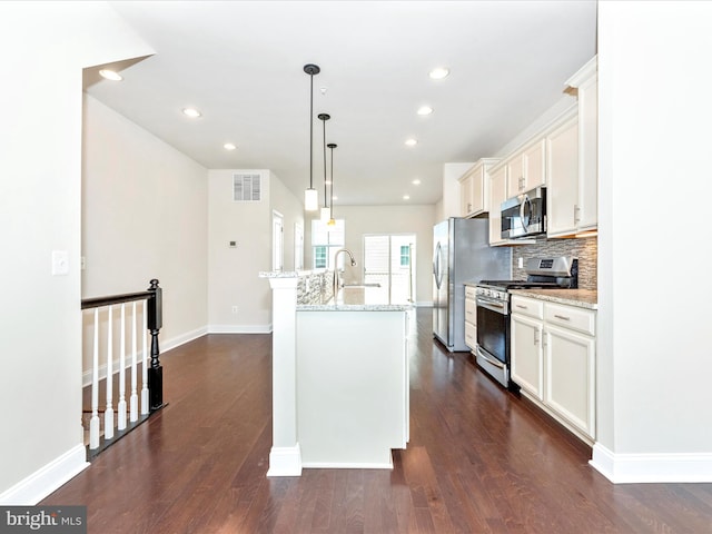 kitchen with a center island with sink, appliances with stainless steel finishes, dark hardwood / wood-style floors, and hanging light fixtures