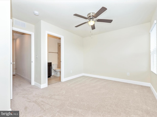 unfurnished bedroom with ceiling fan, ensuite bath, and light carpet