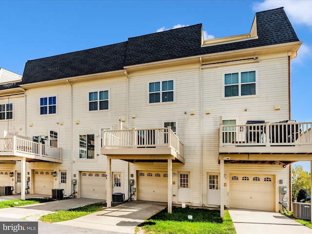 rear view of property with cooling unit, a balcony, and a garage