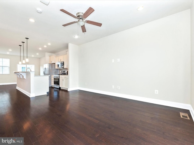 unfurnished living room with sink, dark hardwood / wood-style flooring, and ceiling fan