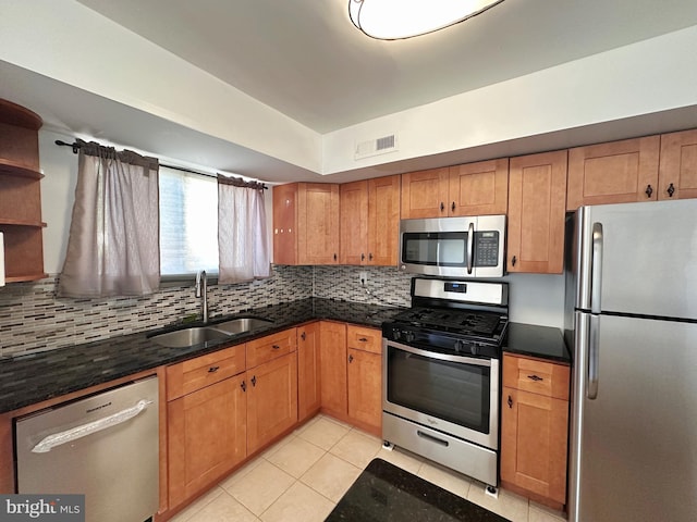 kitchen with sink, stainless steel appliances, tasteful backsplash, dark stone countertops, and light tile patterned flooring