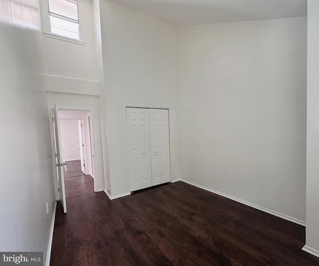 spare room with a towering ceiling and dark hardwood / wood-style floors