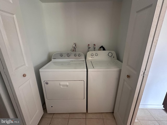 clothes washing area featuring washer and dryer and light tile patterned flooring