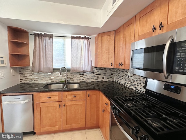 kitchen with backsplash, dark stone counters, sink, light tile patterned floors, and appliances with stainless steel finishes