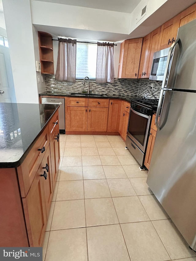 kitchen with stainless steel appliances, tasteful backsplash, dark stone countertops, and sink