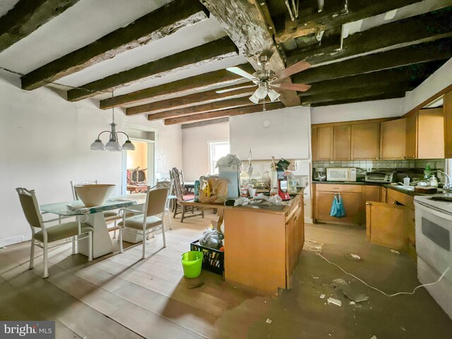 dining space featuring ceiling fan with notable chandelier, beam ceiling, sink, and light hardwood / wood-style flooring