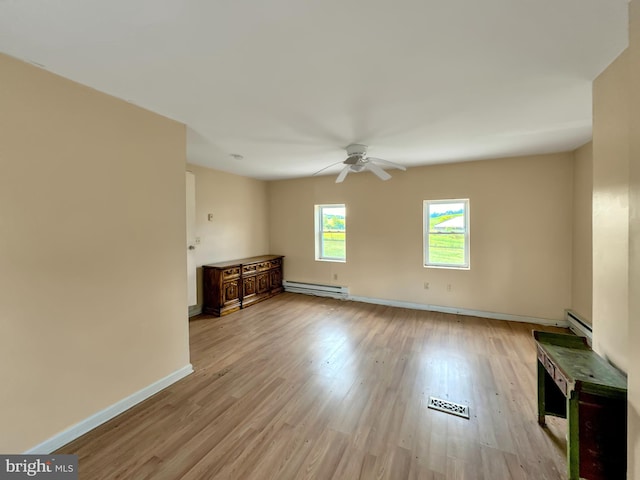 empty room featuring ceiling fan, light wood-type flooring, and a baseboard heating unit