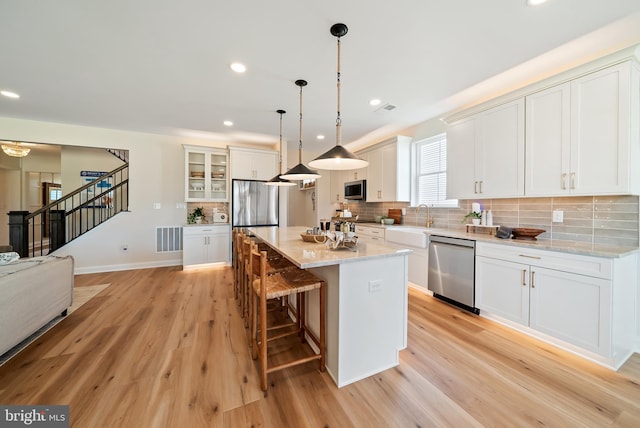 kitchen featuring light hardwood / wood-style flooring, stainless steel appliances, white cabinets, and a center island