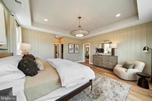 bedroom featuring a raised ceiling and light hardwood / wood-style floors