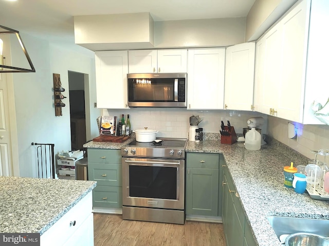 kitchen with white cabinetry, light stone countertops, light hardwood / wood-style flooring, backsplash, and appliances with stainless steel finishes