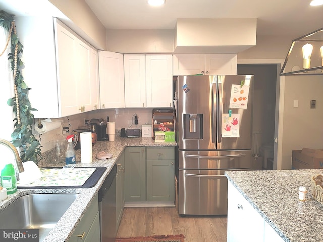 kitchen with stainless steel appliances, sink, light hardwood / wood-style flooring, white cabinets, and hanging light fixtures