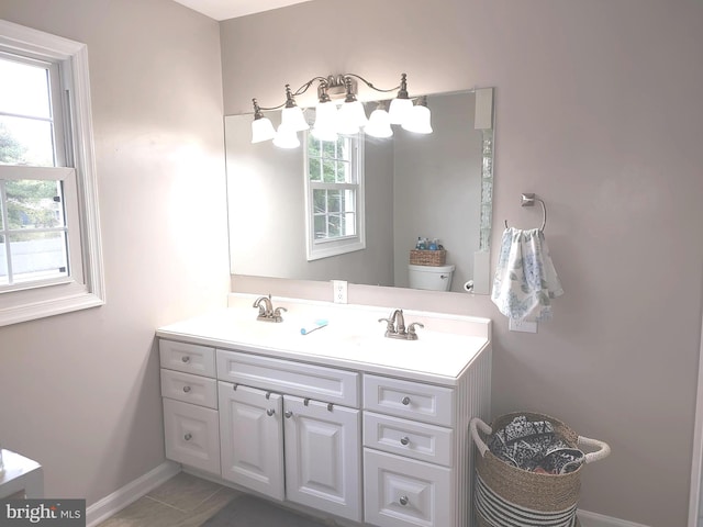 bathroom with tile patterned flooring, vanity, a healthy amount of sunlight, and toilet