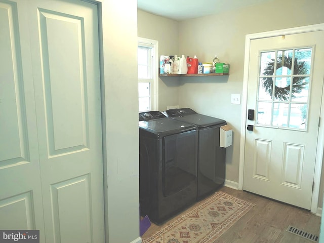 laundry area featuring a healthy amount of sunlight, wood-type flooring, and separate washer and dryer