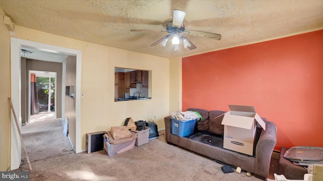 living area with ceiling fan, light colored carpet, and a textured ceiling