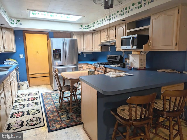 kitchen with sink, kitchen peninsula, a kitchen bar, stainless steel appliances, and baseboard heating