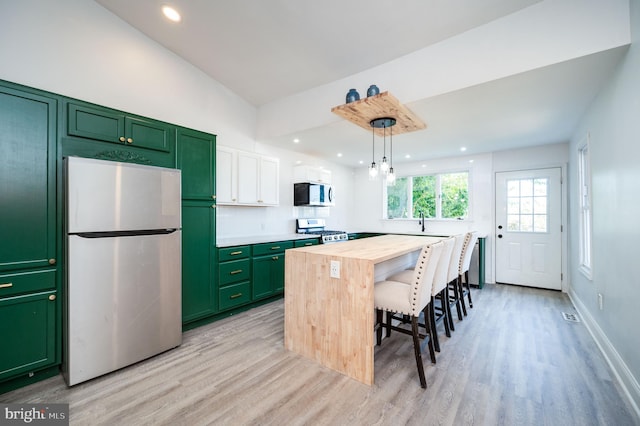 kitchen featuring stove, hanging light fixtures, wooden counters, stainless steel refrigerator, and light hardwood / wood-style floors