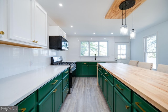 kitchen with white cabinets, green cabinetry, stainless steel gas stove, light hardwood / wood-style flooring, and decorative light fixtures