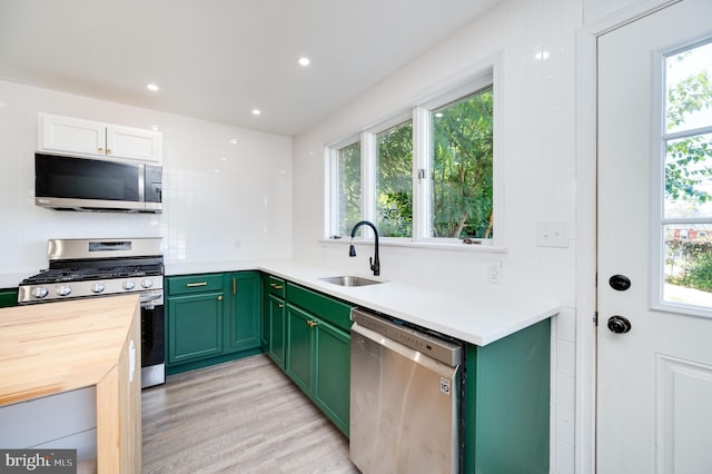 kitchen featuring appliances with stainless steel finishes, light hardwood / wood-style floors, white cabinetry, sink, and green cabinets