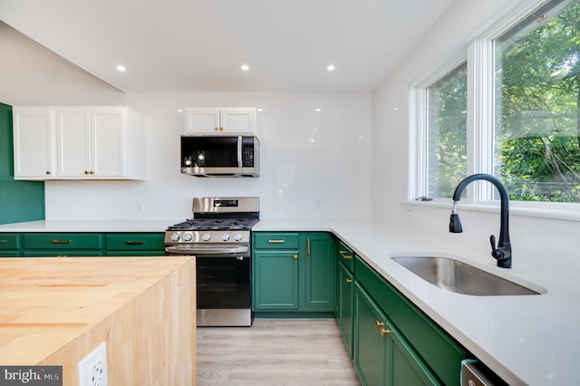 kitchen with white cabinets, sink, butcher block countertops, appliances with stainless steel finishes, and light wood-type flooring