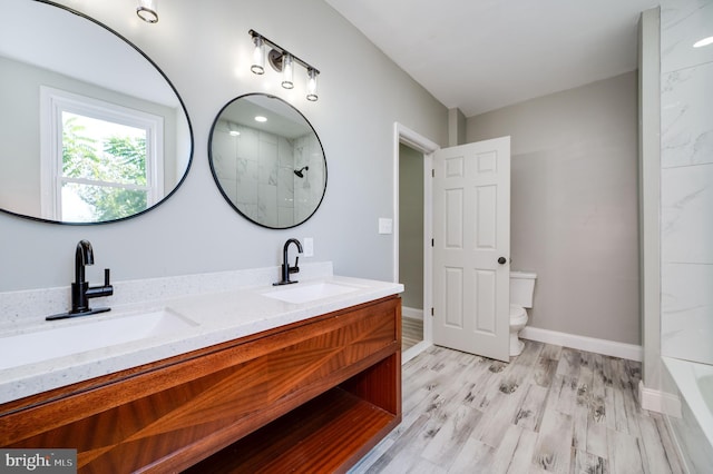 bathroom with wood-type flooring, vanity, toilet, and a shower