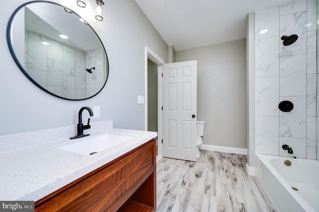 full bathroom featuring wood-type flooring, tiled shower / bath combo, vanity, and toilet