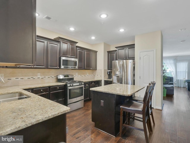 kitchen featuring a breakfast bar area, stainless steel appliances, a center island, dark hardwood / wood-style floors, and sink