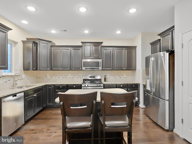 11487 Stockport Pl, White Plains, MD 20695 - kitchen with stainless steel appliances, a center island, dark wood finished floors, a sink, and backsplash