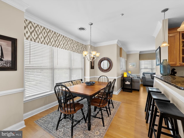 dining room featuring light wood-type flooring, crown molding, and an inviting chandelier