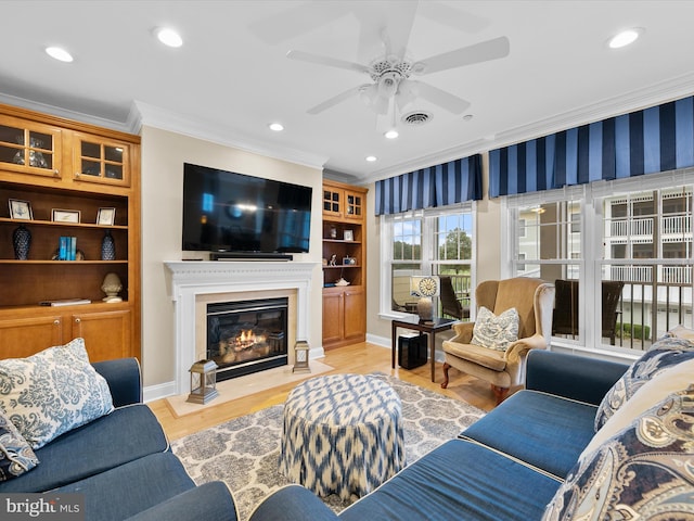 living room with light hardwood / wood-style flooring, ceiling fan, and crown molding