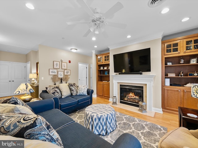 living room featuring light hardwood / wood-style flooring, ceiling fan, and ornamental molding