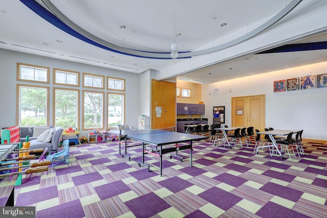 game room with a tray ceiling, a towering ceiling, and carpet