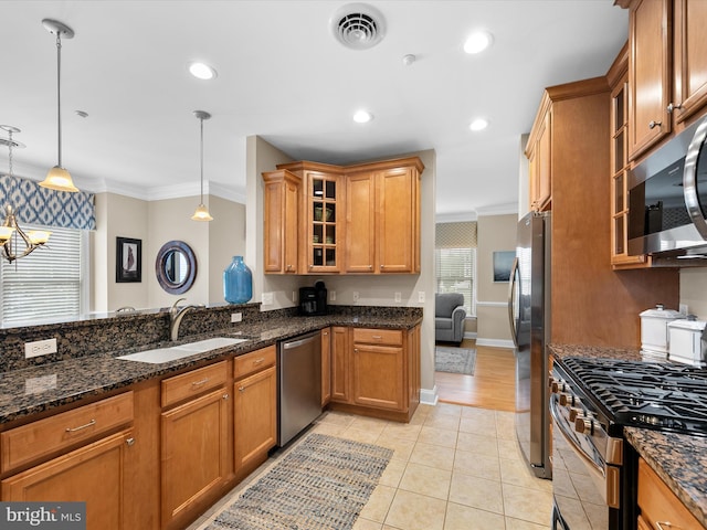 kitchen with ornamental molding, sink, decorative light fixtures, and stainless steel appliances