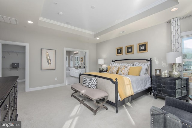 carpeted bedroom with a raised ceiling, ornamental molding, a walk in closet, a closet, and ensuite bathroom