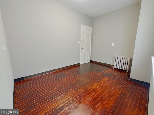 unfurnished room featuring radiator and dark wood-type flooring