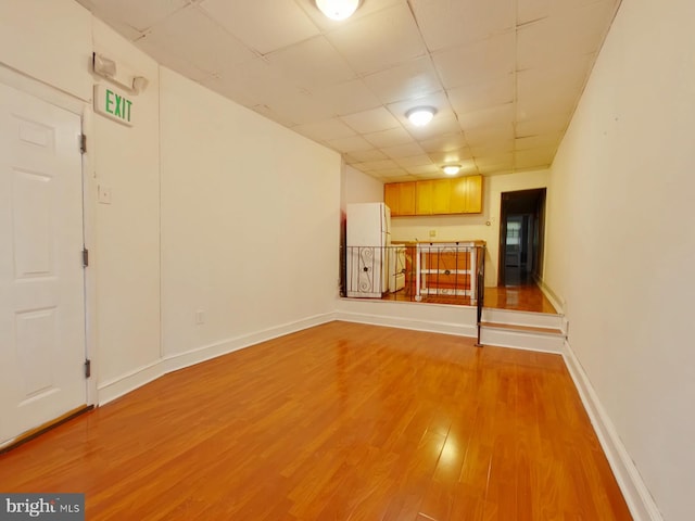 unfurnished living room with a drop ceiling and hardwood / wood-style flooring